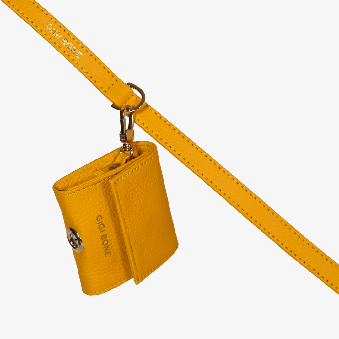 Portabolsas higiénicas de piel color amarillo. Logo GiGi BONE impreso en el cuero en letras doradas a juego con los herrajes Ojal de metal dorado en la parte baja para facilitar la dispensa de bolsas Hecho a mano con piel italiana de curtido vegetal