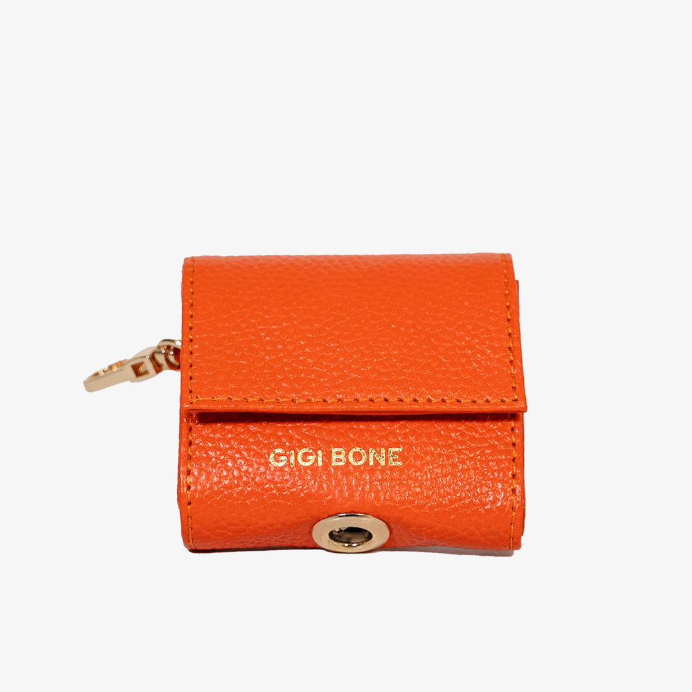 Portabolsas higiénicas de piel color rojo naranja. Logo GiGi BONE impreso en el cuero en letras doradas a juego con los herrajes Ojal de metal dorado en la parte baja para facilitar la dispensa de bolsas Hecho a mano con piel italiana de curtido vegetal